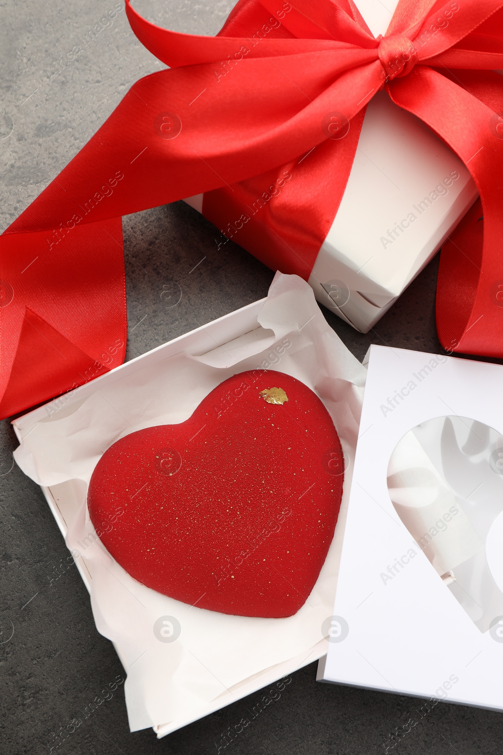 Photo of Heart shaped chocolate and gift box on grey table, flat lay