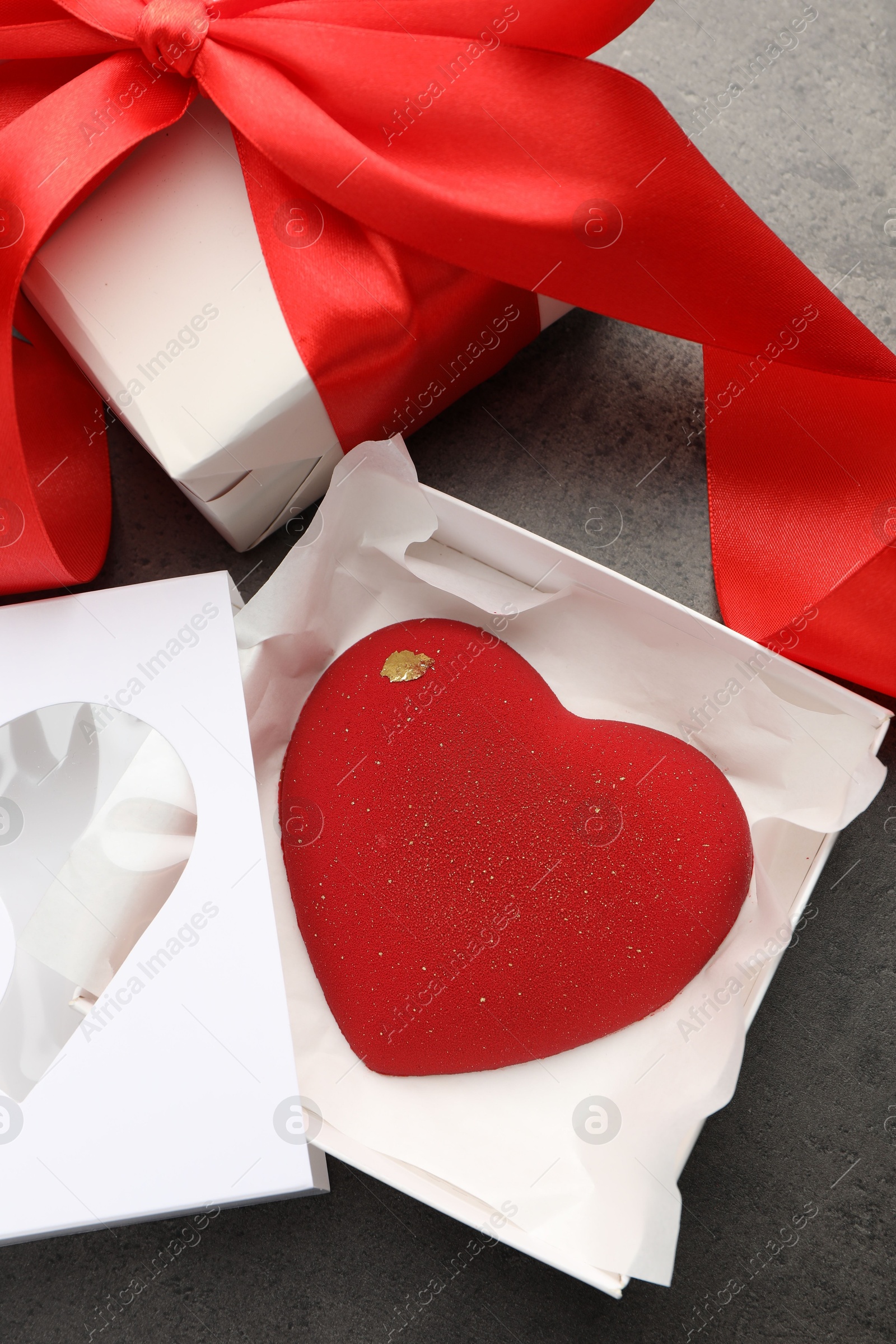 Photo of Heart shaped chocolate and gift box on grey table, flat lay