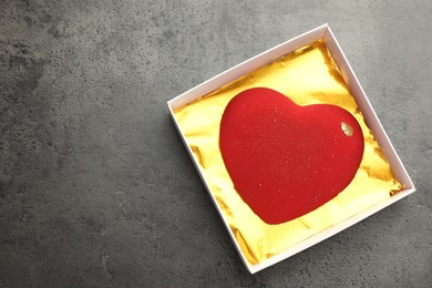 Photo of Heart shaped chocolate in box on grey table, top view. Space for text