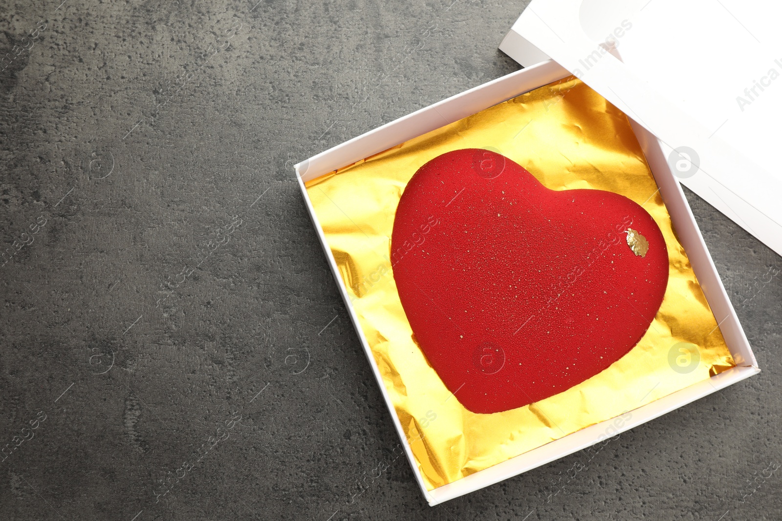 Photo of Heart shaped chocolate in box on grey table, top view. Space for text