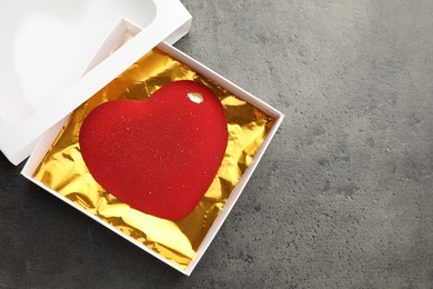 Photo of Heart shaped chocolate in box on grey table, top view. Space for text