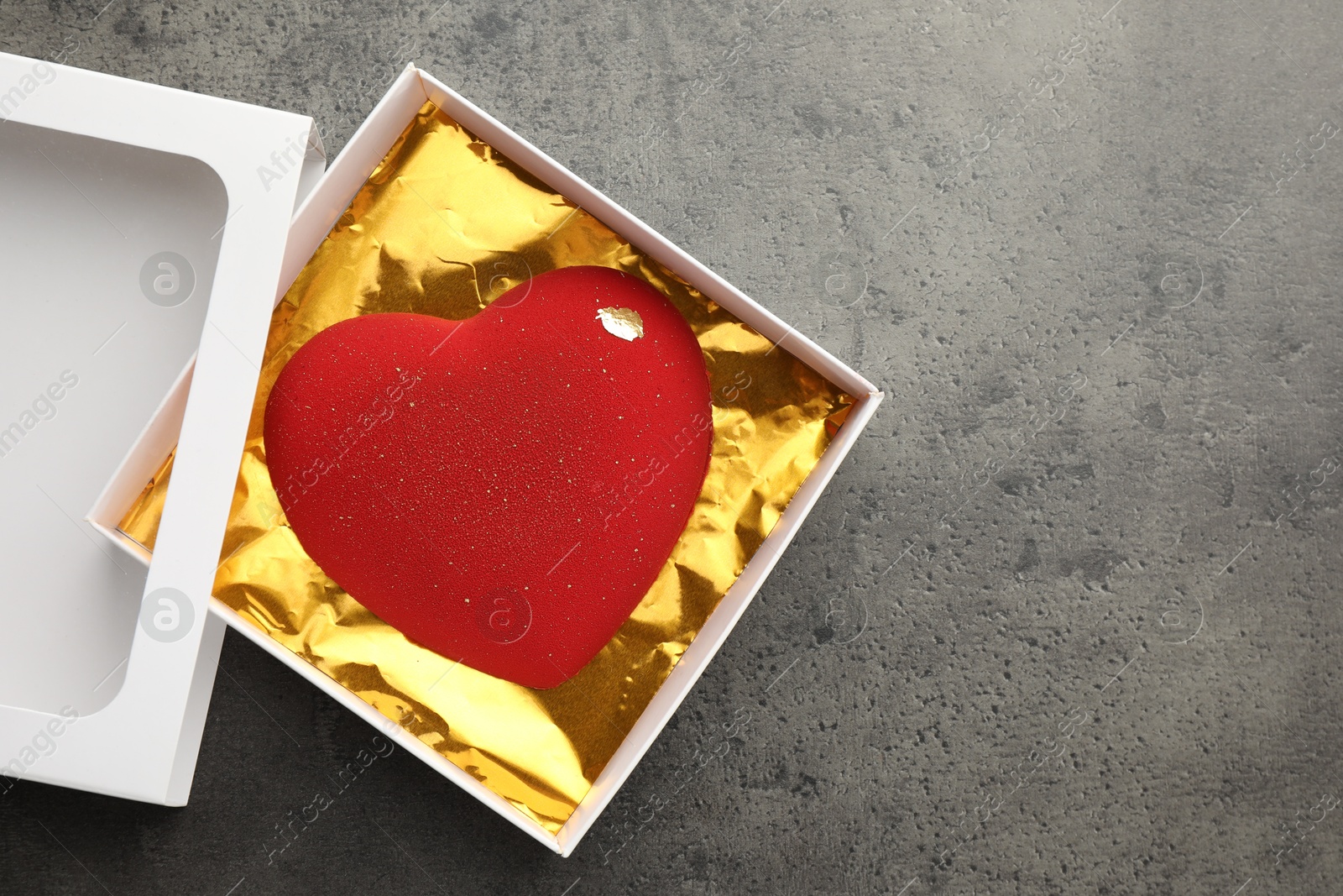 Photo of Heart shaped chocolate in box on grey table, top view. Space for text