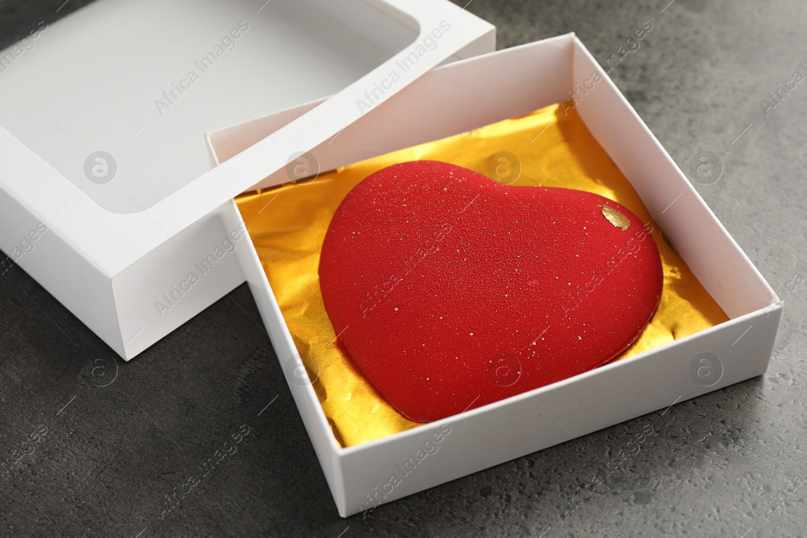 Photo of Heart shaped chocolate in box on grey table, closeup