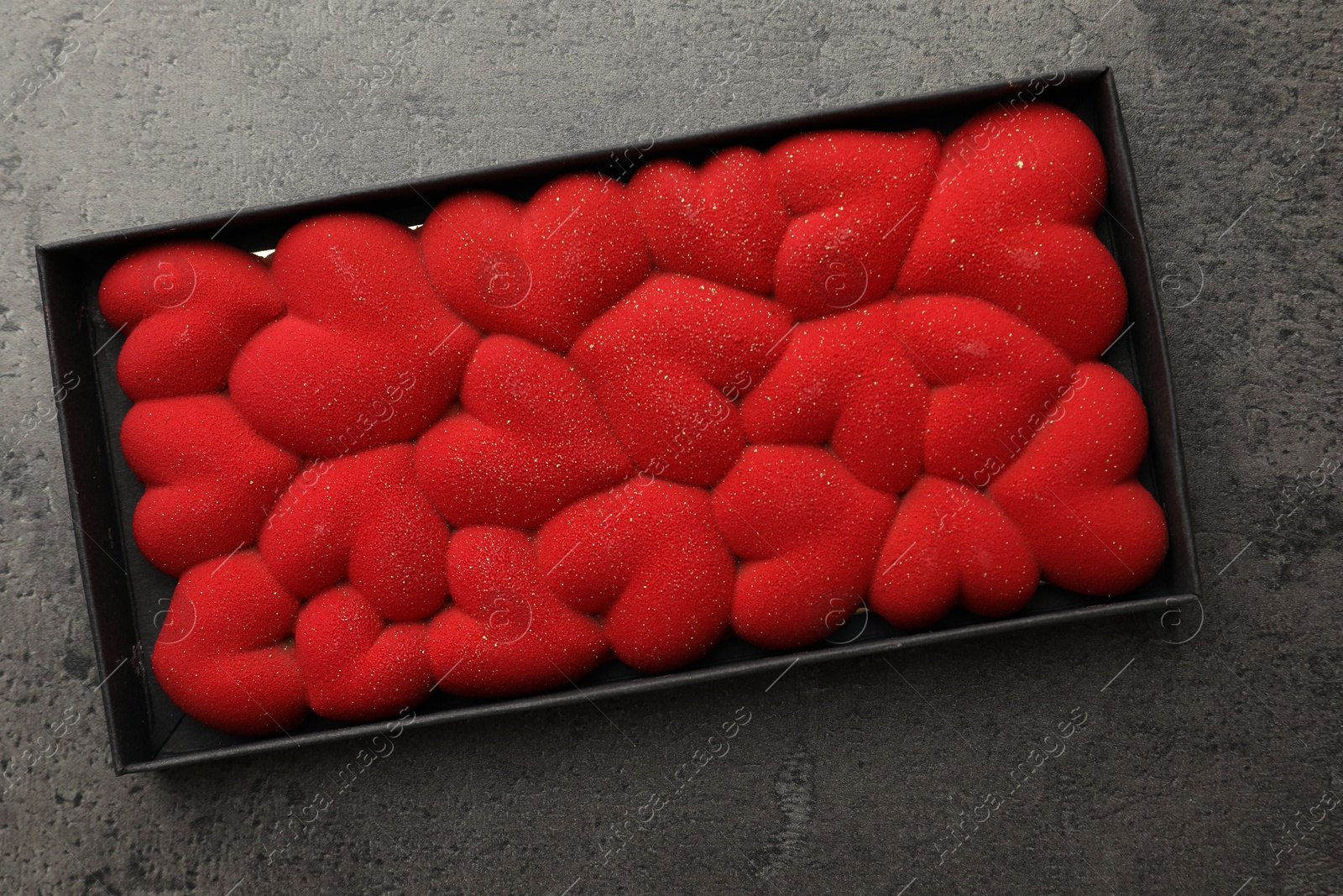 Photo of Chocolate bar decorated with hearts in box on grey table, top view