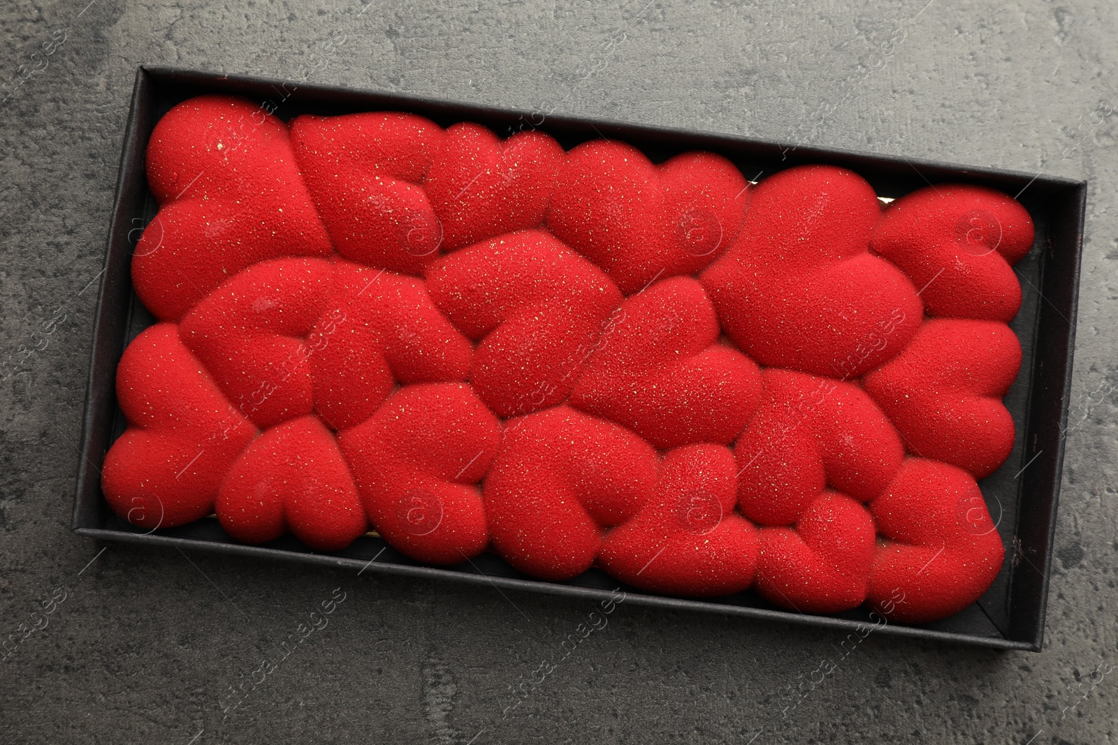 Photo of Chocolate bar decorated with hearts in box on grey table, top view