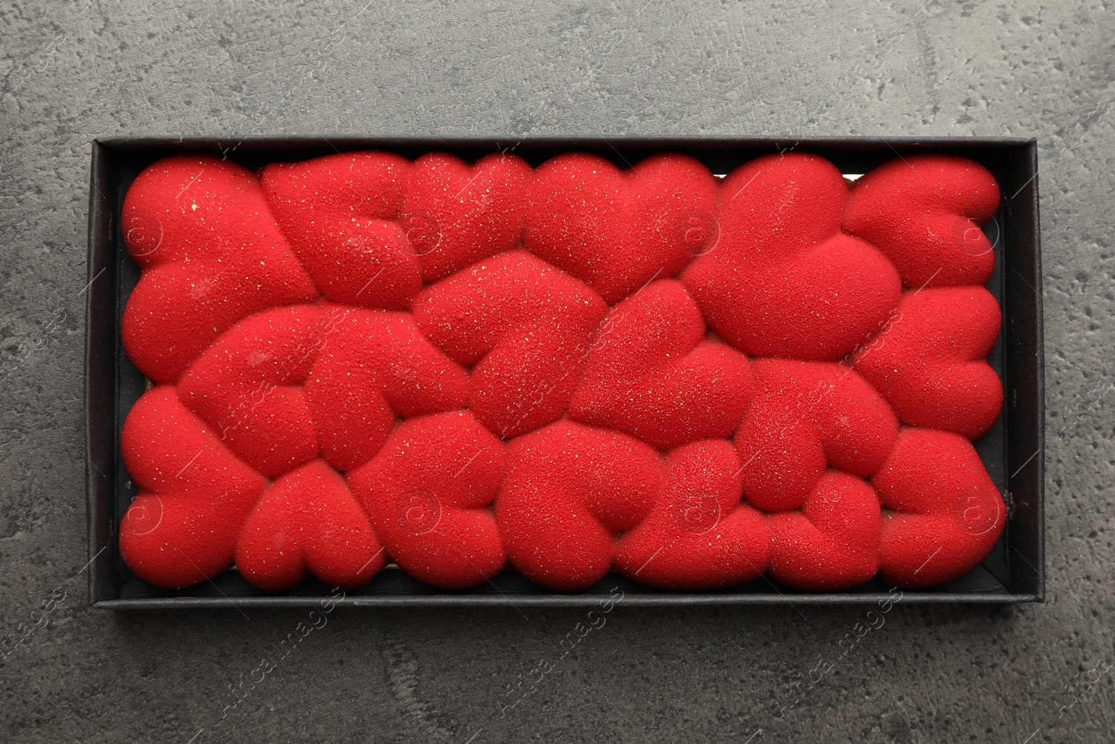 Photo of Chocolate bar decorated with hearts in box on grey table, top view