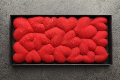 Photo of Chocolate bar decorated with hearts in box on grey table, top view