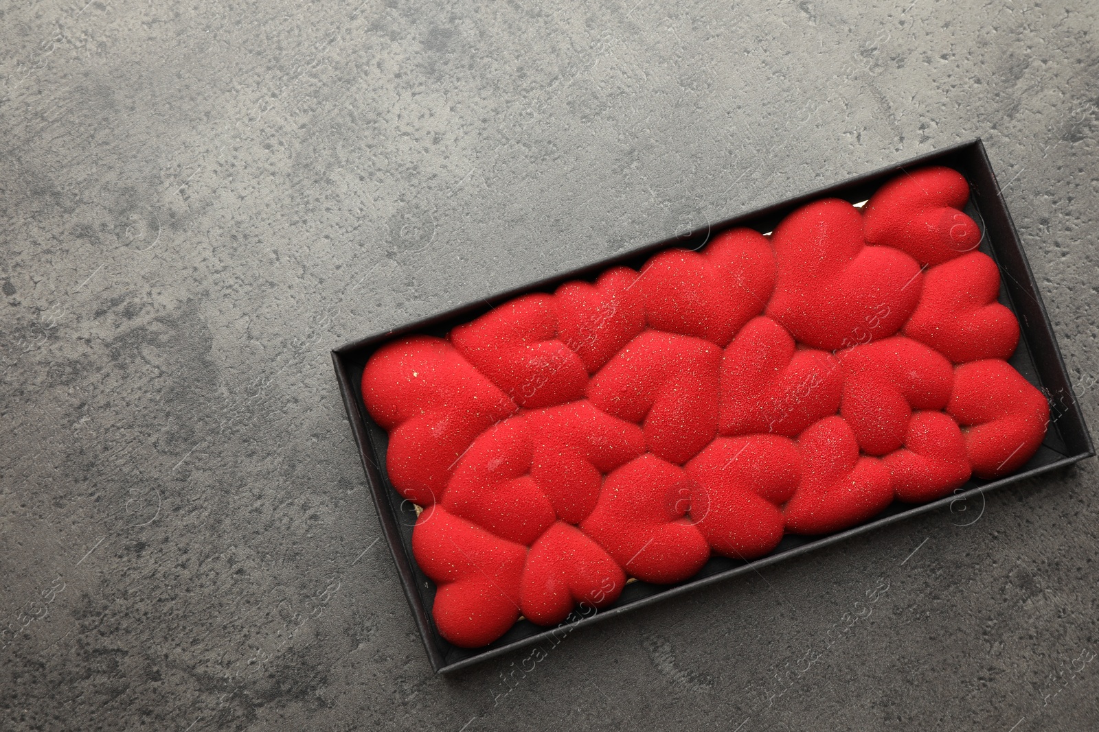 Photo of Chocolate bar decorated with hearts in box on grey table, top view. Space for text