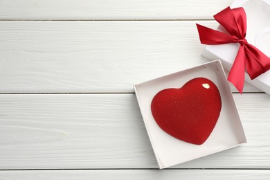 Photo of Heart shaped chocolate in box on white wooden table, flat lay. Space for text