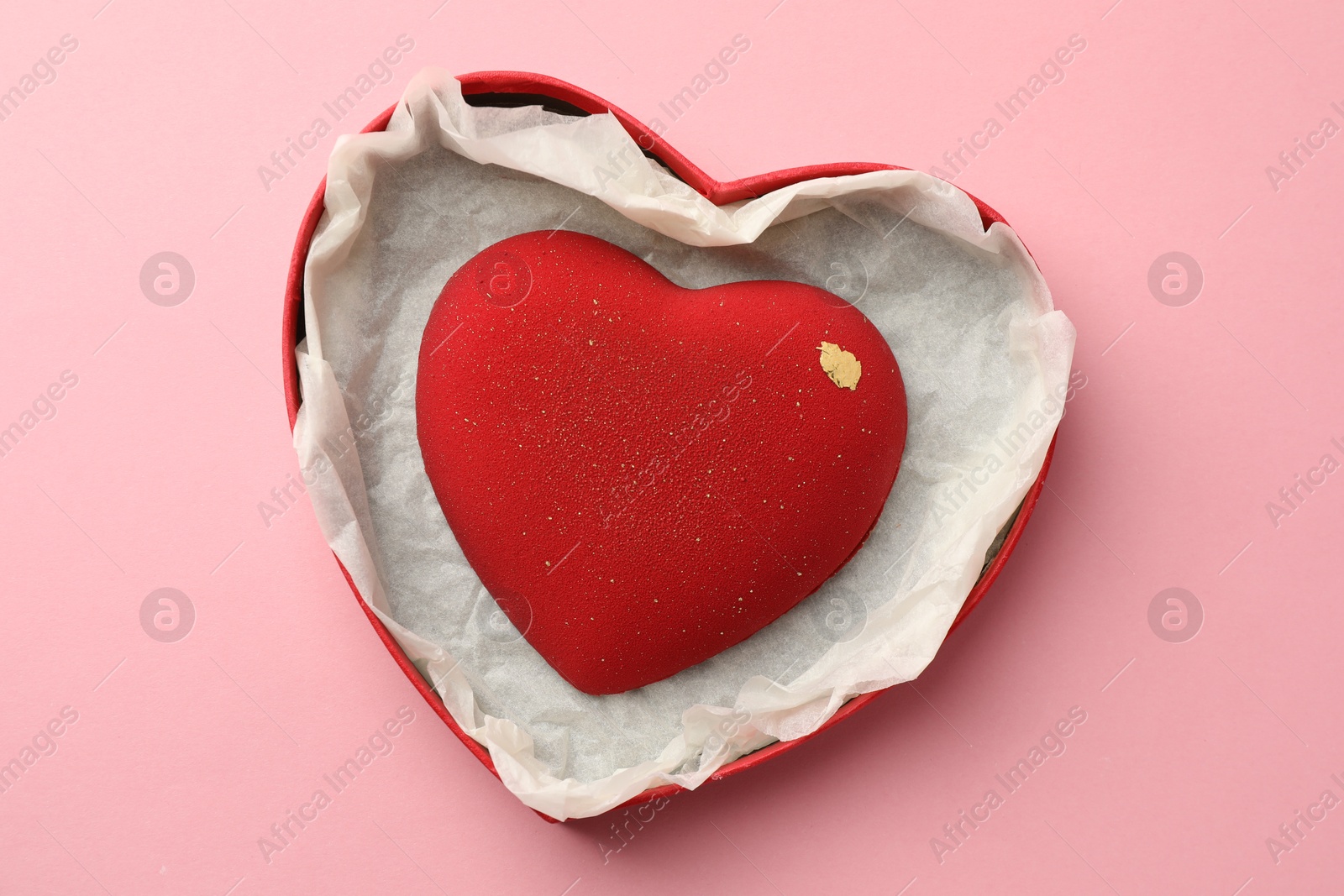 Photo of Heart shaped chocolate in box on pink background, top view