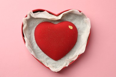 Photo of Heart shaped chocolate in box on pink background, top view