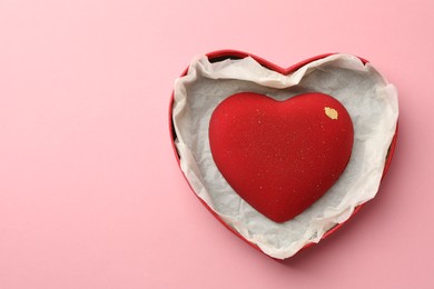 Photo of Heart shaped chocolate in box on pink background, top view. Space for text