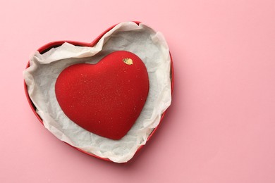 Photo of Heart shaped chocolate in box on pink background, top view. Space for text