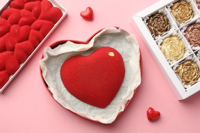 Photo of Heart shaped chocolate and other candies on pink background, flat lay