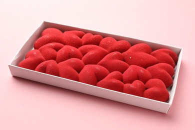 Photo of Chocolate bar decorated with hearts in box on pink background, closeup