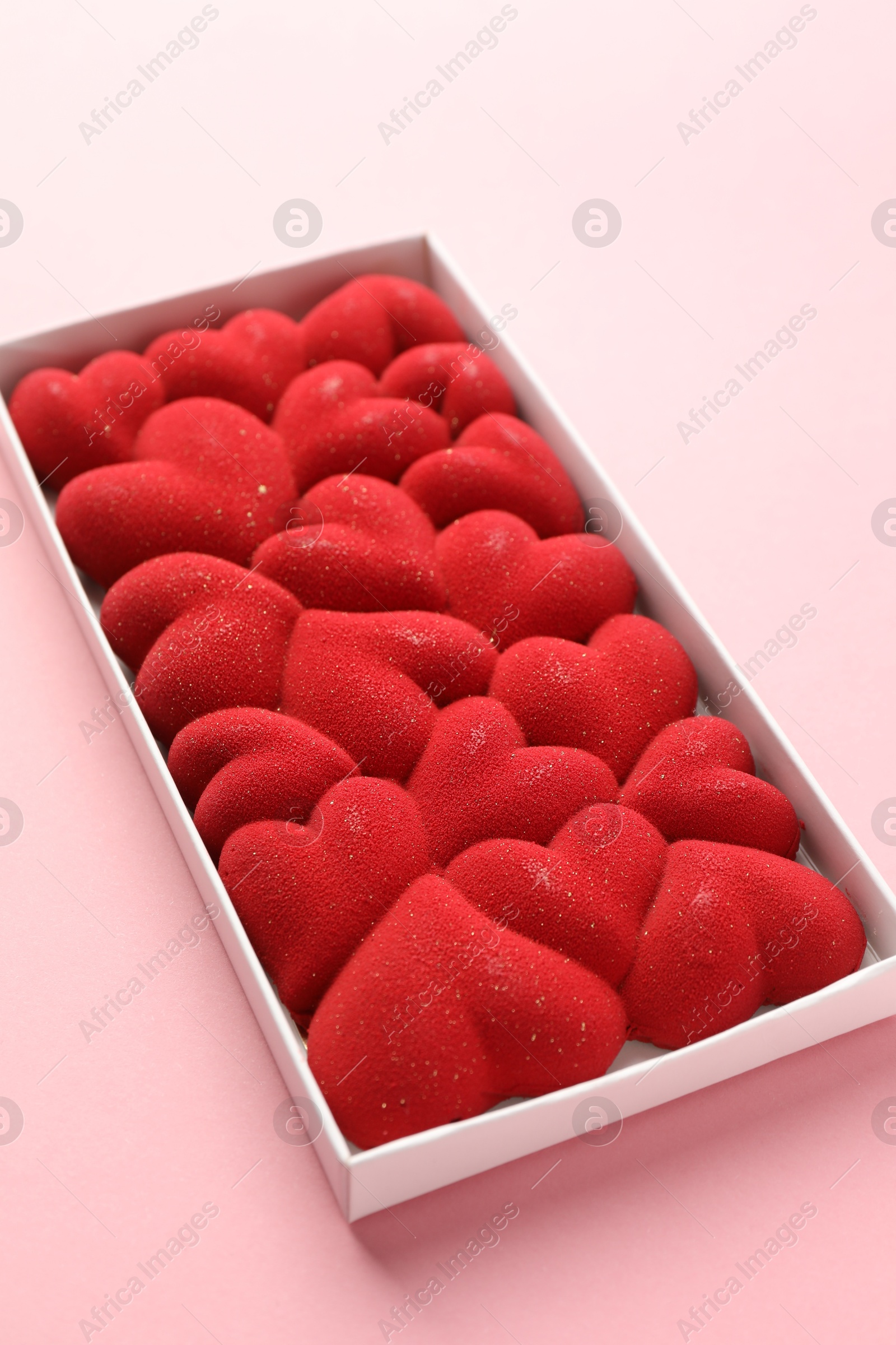 Photo of Chocolate bar decorated with hearts in box on pink background, closeup