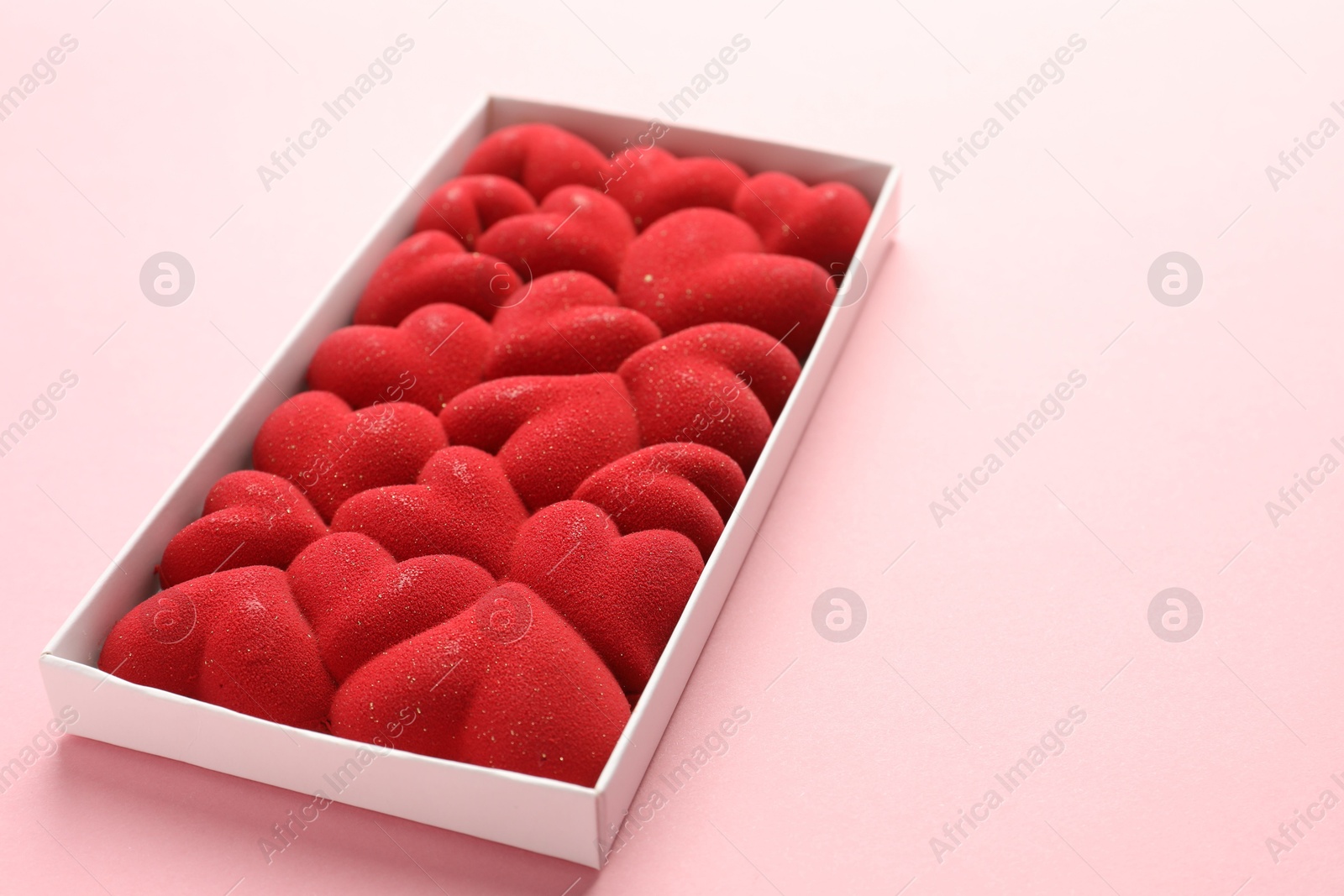 Photo of Chocolate bar decorated with hearts in box on pink background, closeup. Space for text