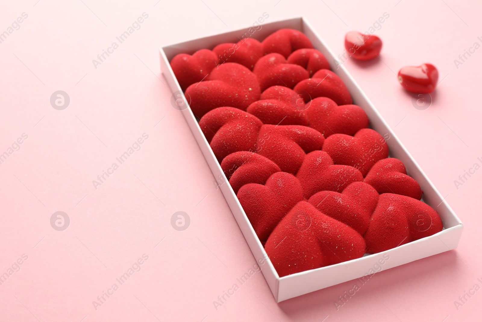 Photo of Chocolate bar decorated with hearts in box on pink background, closeup. Space for text