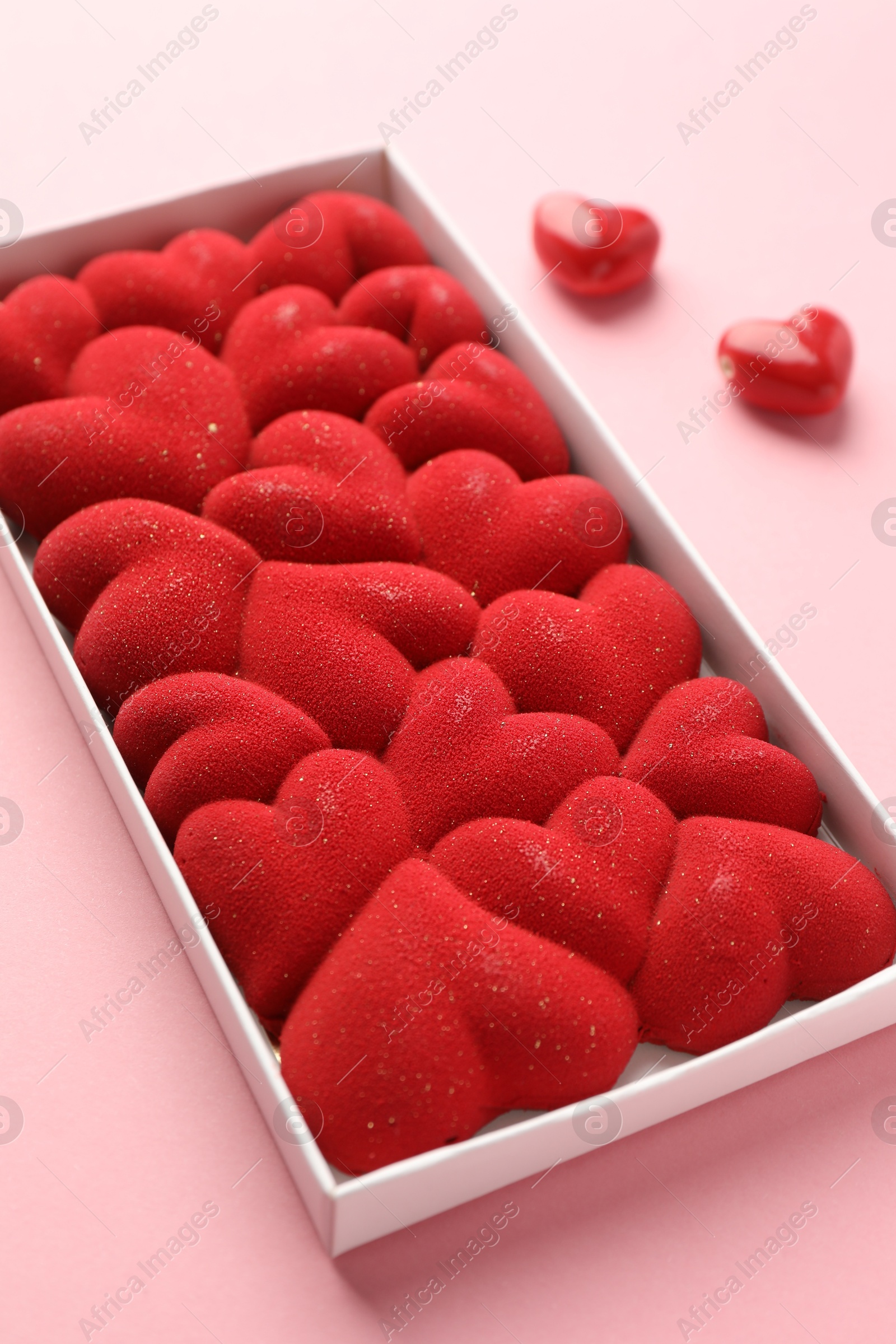 Photo of Chocolate bar decorated with hearts in box on pink background, closeup