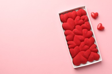 Photo of Chocolate bar decorated with hearts in box on pink background, flat lay. Space for text