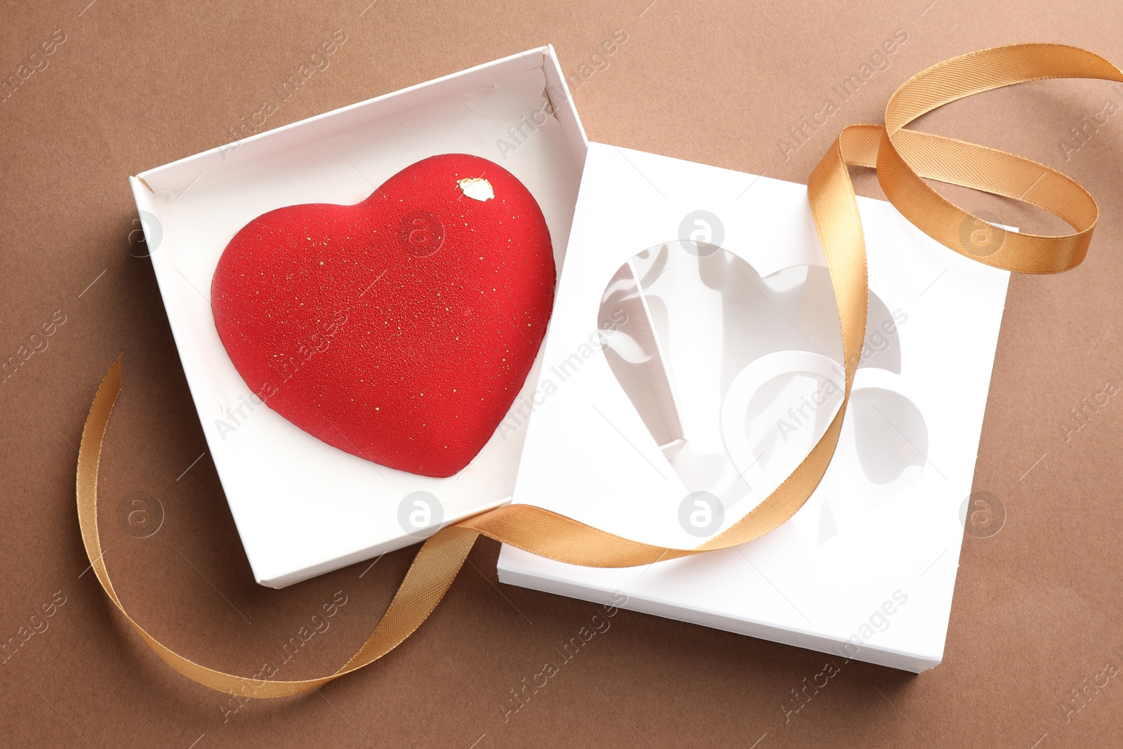 Photo of Heart shaped chocolate in box on brown background, top view