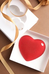 Photo of Heart shaped chocolate in box on brown background, top view