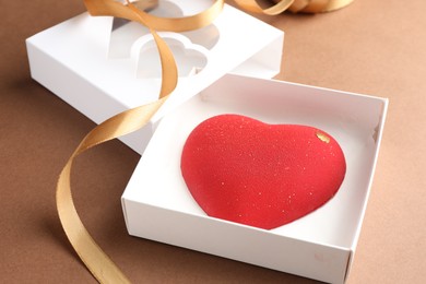 Photo of Heart shaped chocolate in box on brown background, closeup