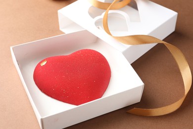 Photo of Heart shaped chocolate in box on brown background, closeup