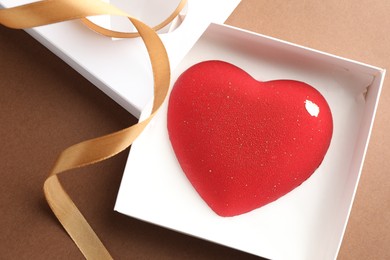 Photo of Heart shaped chocolate in box on brown background, top view