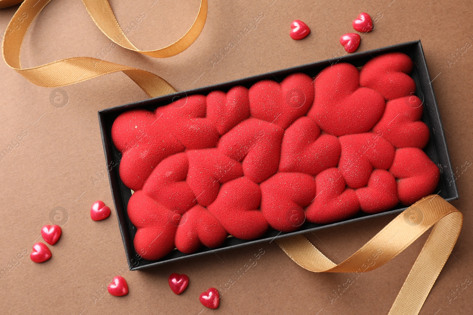 Photo of Chocolate bar decorated with hearts and confetti on brown background, top view