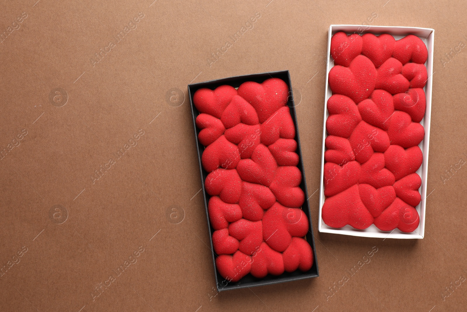 Photo of Chocolate bars decorated with hearts on brown background, top view. Space for text