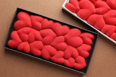 Photo of Chocolate bars decorated with hearts on brown background, top view