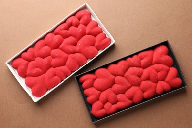 Photo of Chocolate bars decorated with hearts on brown background, top view