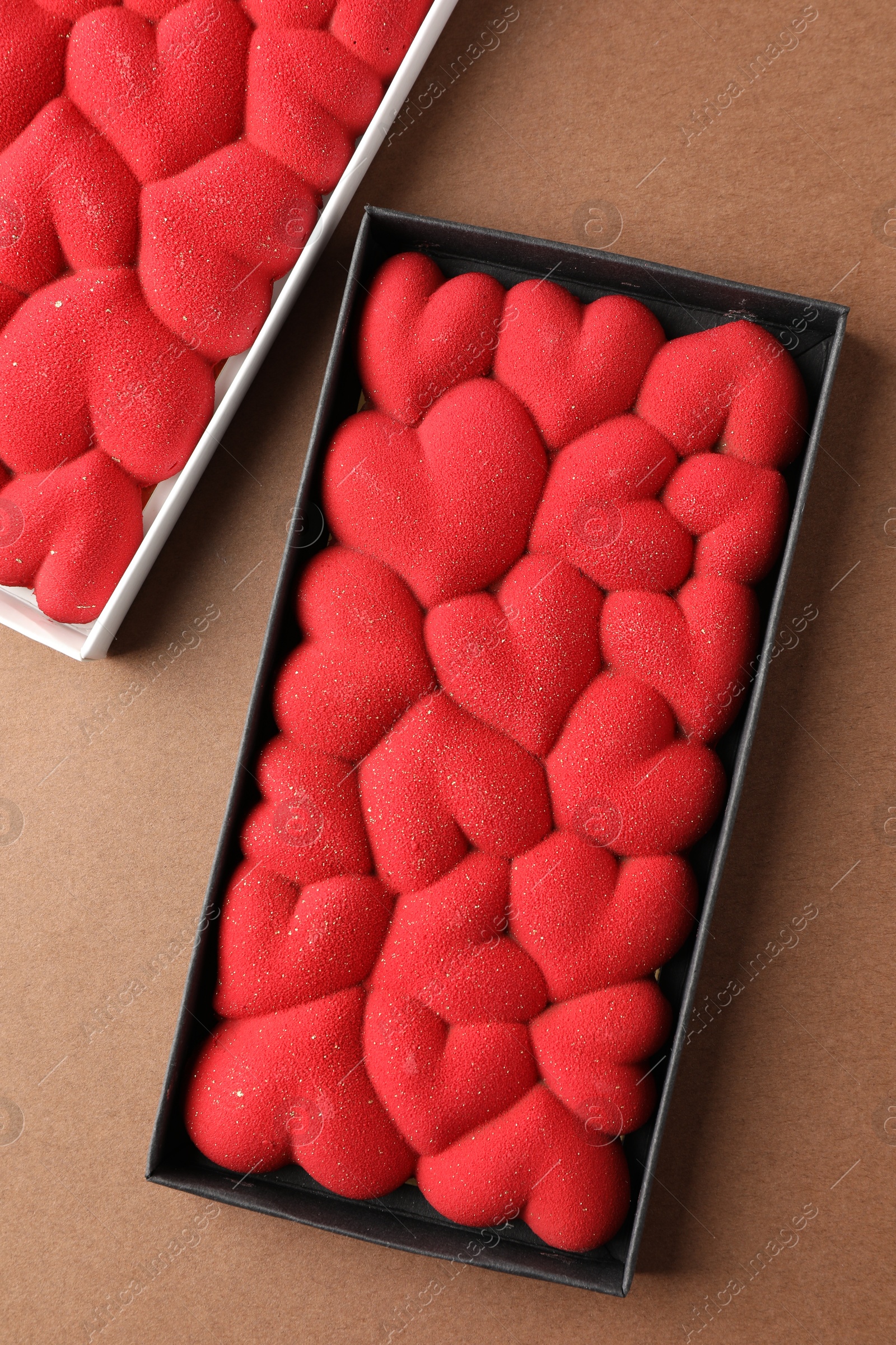 Photo of Chocolate bars decorated with hearts on brown background, top view