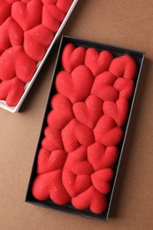 Photo of Chocolate bars decorated with hearts on brown background, top view