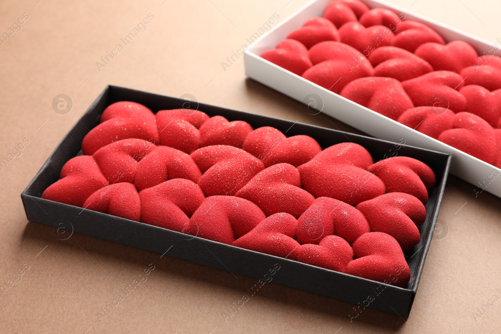 Photo of Chocolate bars decorated with hearts on brown background, closeup