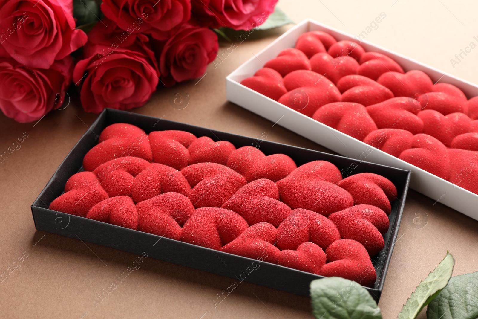 Photo of Chocolate bars decorated with hearts and roses on brown background, closeup