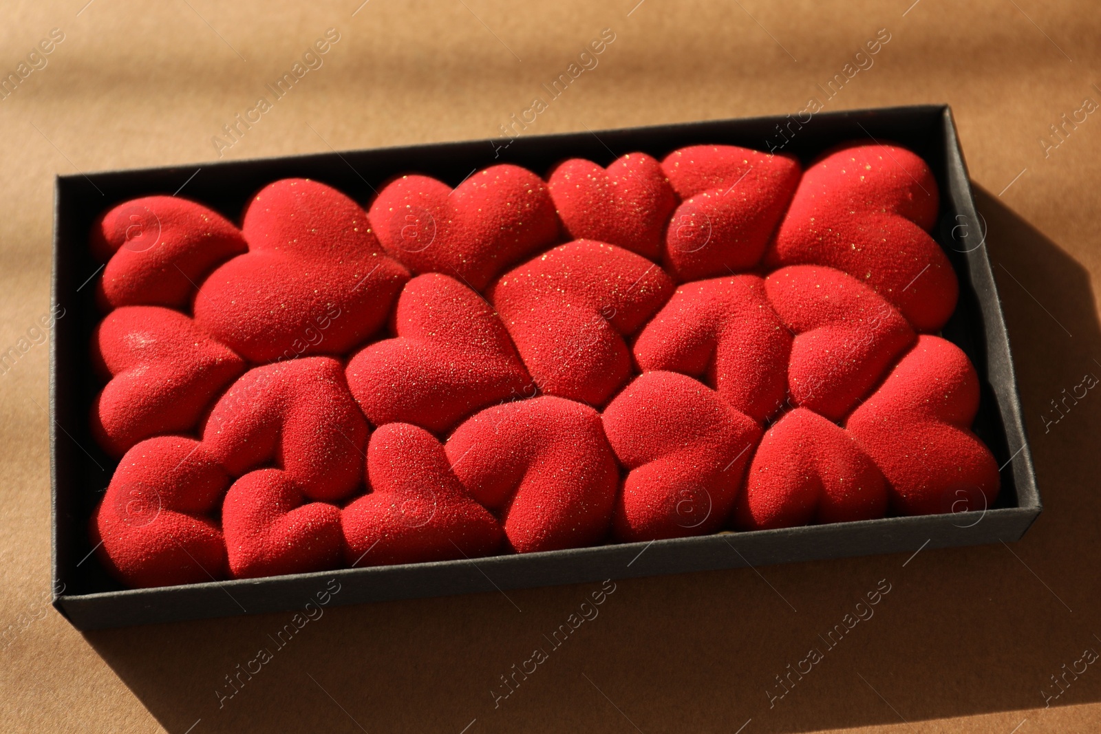 Photo of Chocolate bar decorated with hearts on brown background, closeup