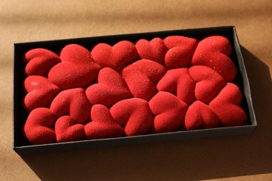 Photo of Chocolate bar decorated with hearts on brown background, closeup