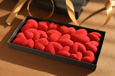 Photo of Chocolate bar decorated with hearts on brown background, closeup