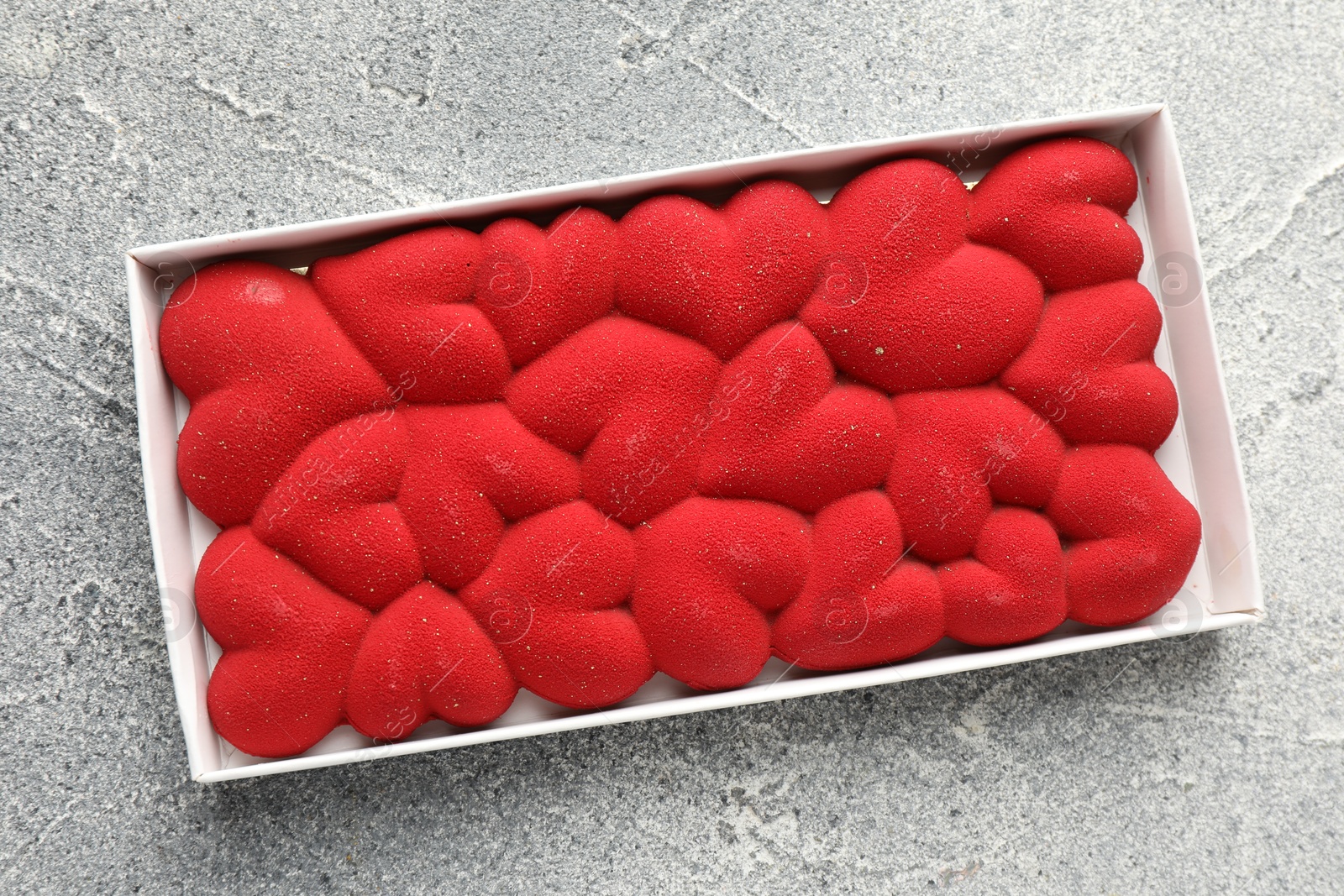 Photo of Chocolate bar decorated with hearts on grey textured background, top view