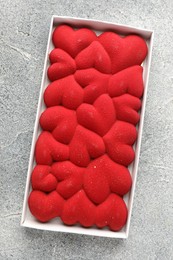 Photo of Chocolate bar decorated with hearts on grey textured background, top view