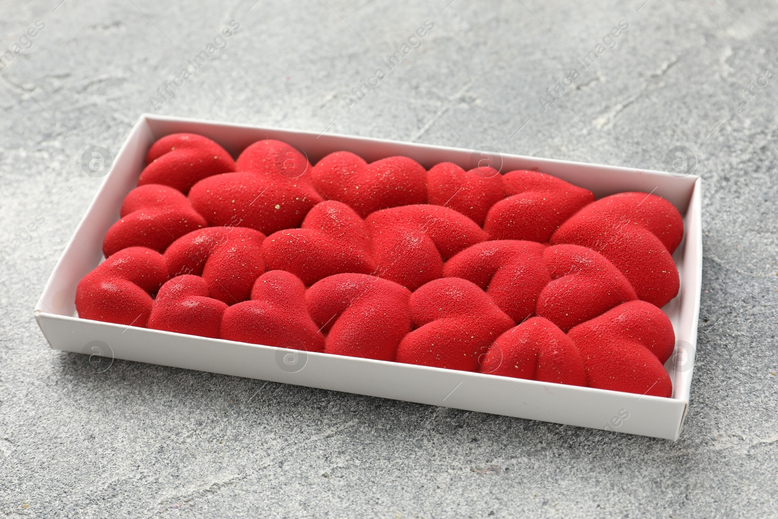 Photo of Chocolate bar decorated with hearts on grey textured background, closeup