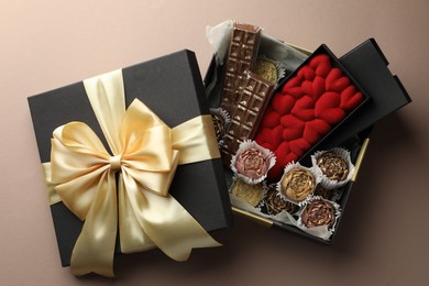 Photo of Different delicious chocolate sweets in box on beige background, top view