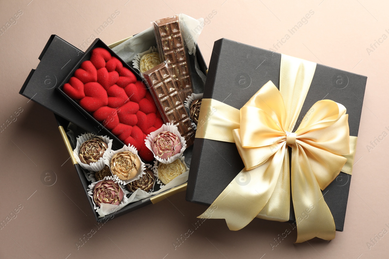 Photo of Different delicious chocolate sweets in box on beige background, top view