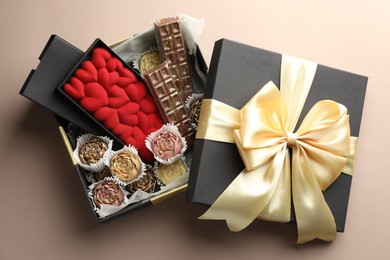 Photo of Different delicious chocolate sweets in box on beige background, top view