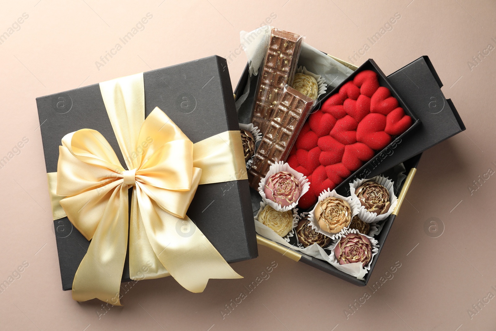 Photo of Different delicious chocolate sweets in box on beige background, top view