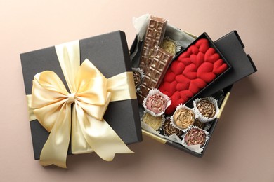 Photo of Different delicious chocolate sweets in box on beige background, top view