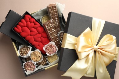 Photo of Different delicious chocolate sweets in box on beige background, top view