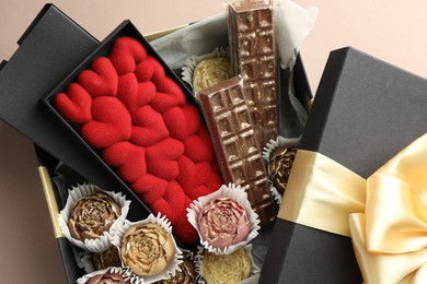 Photo of Different delicious chocolate sweets in box on beige background, top view